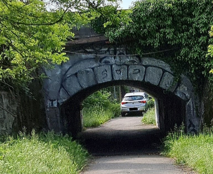 Un’auto percorre la pista ciclabile e passa sotto la ferrovia